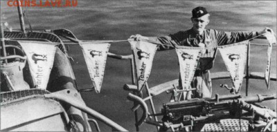 Член команды U-564 (серияVIIC) держит победные флаги своей лодки, лодка претендует на потопление трех транспортов и трех танкеров, на каждом флаге нарисована эмблема лодки. - U-564 